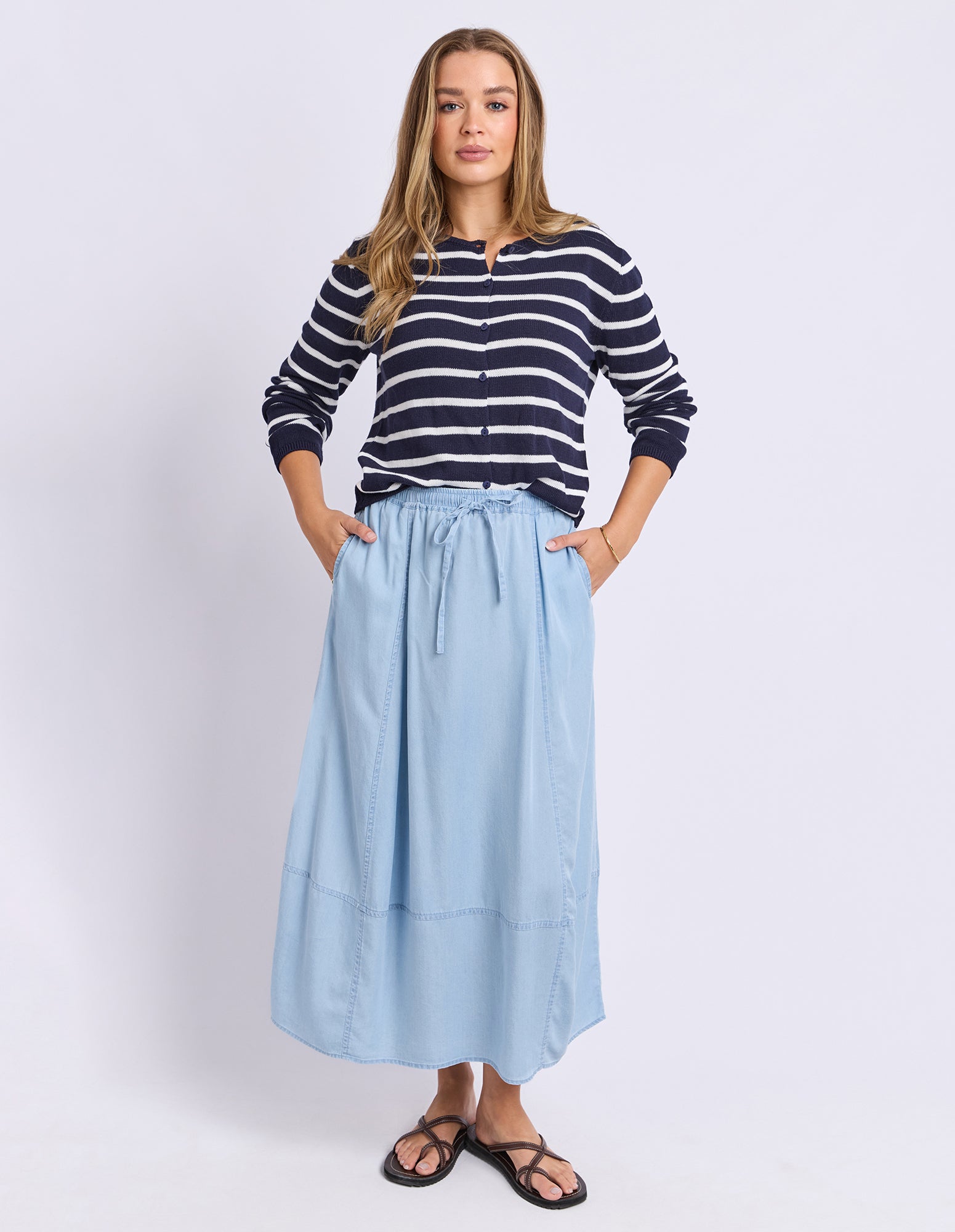 Woman wearing a striped sweater and light blue skirt on a white background