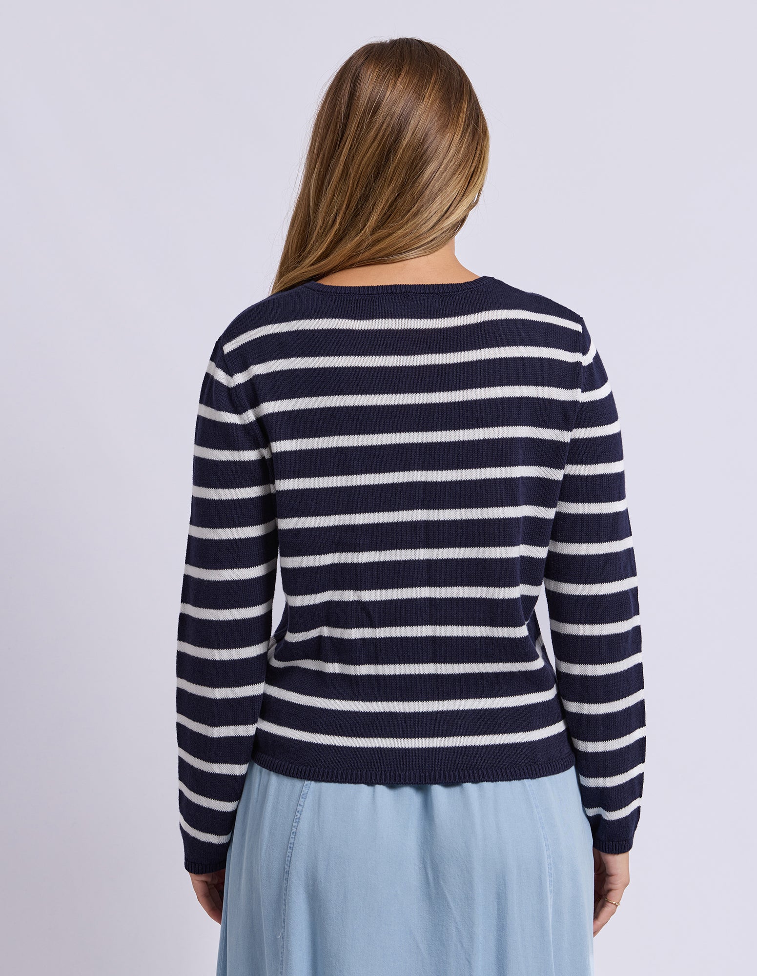 Woman wearing a navy and white striped sweater on a plain background