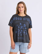 Woman wearing a black t-shirt with blue graphics and text on a plain background