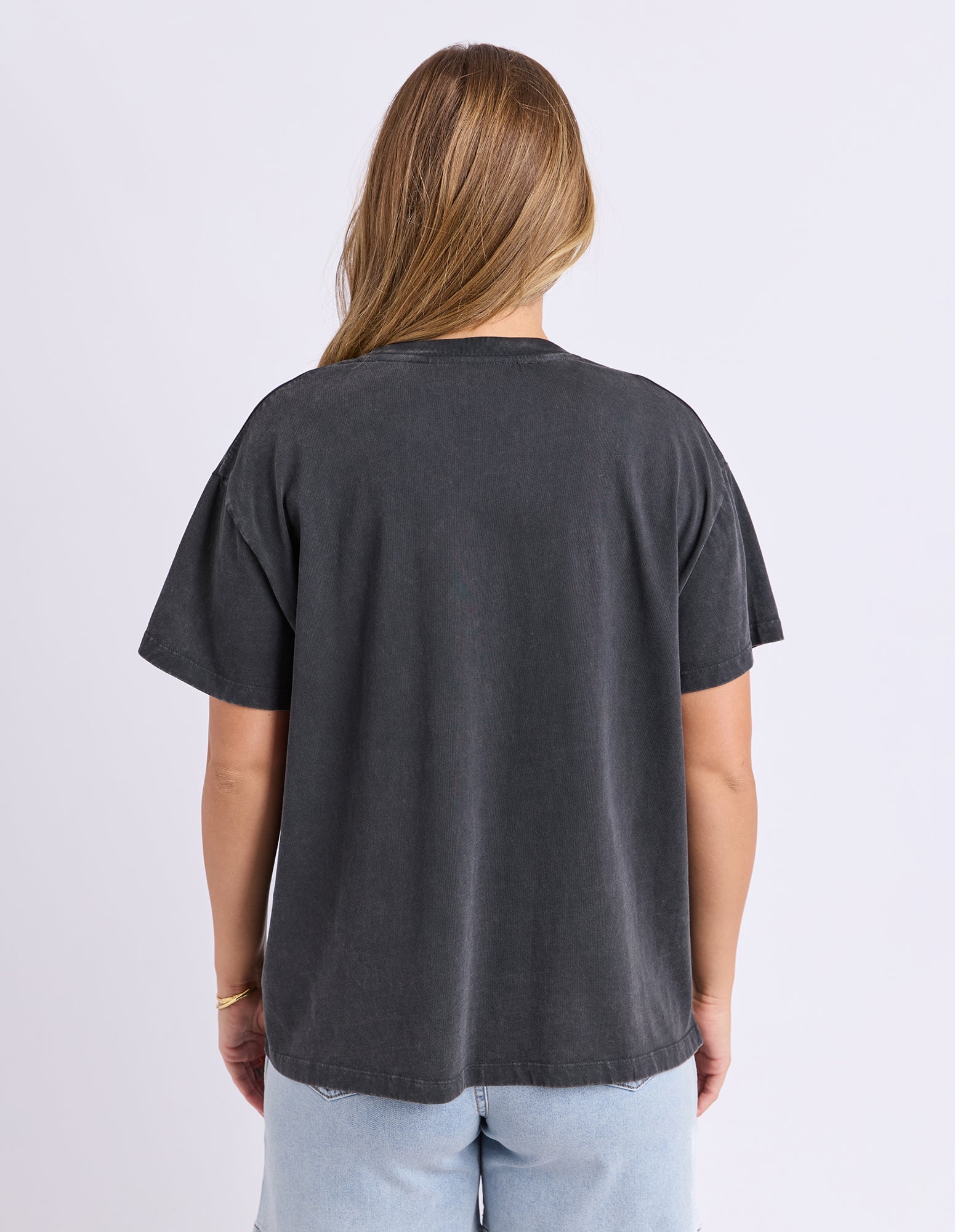 Person wearing a plain black t-shirt on a light gray background