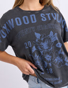 Person wearing a dark gray t-shirt with blue graphics and text on a white background