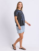 Woman wearing a black t-shirt with text and light blue denim shorts on a white background