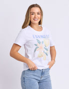 Woman wearing a white t-shirt with floral design and 'FOXMOON' text on a plain background