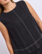 Black sleeveless top with white stitching on a neutral background