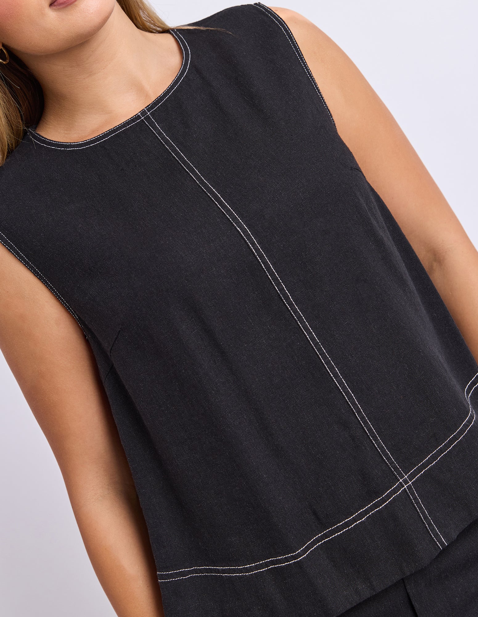 Black sleeveless top with white stitching on a neutral background