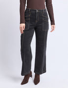 Person wearing dark jeans and brown top on a white background