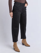 Person wearing black pants and brown boots on a white background
