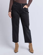 Person wearing black jeans and brown boots on a white background