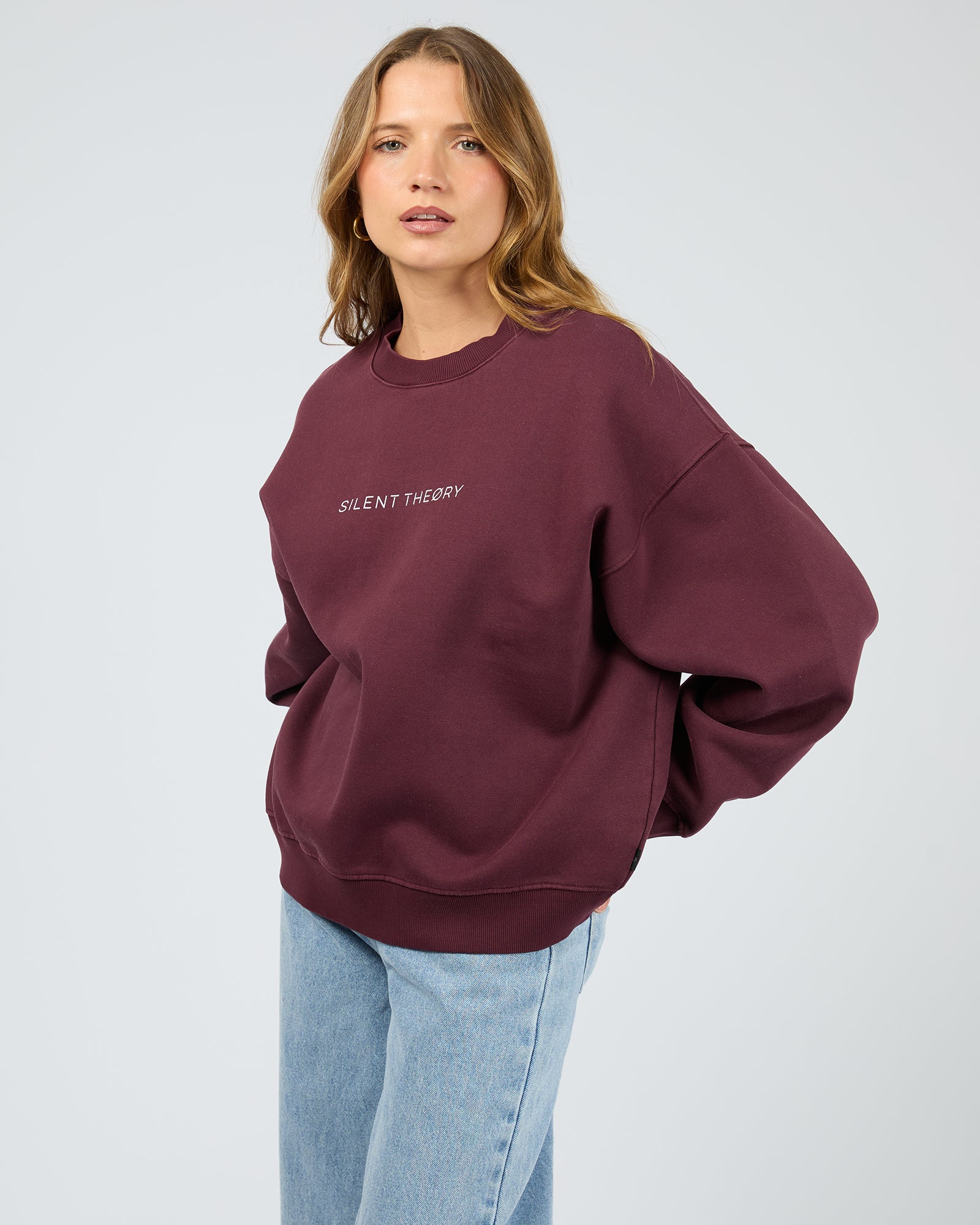 Woman wearing a maroon sweatshirt with 'SILENT THEORY' text on a light gray background