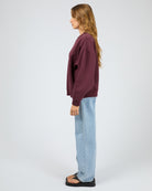 Person wearing a burgundy sweater and light blue jeans on a white background