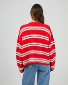 Person wearing a red and white striped sweater on a plain background