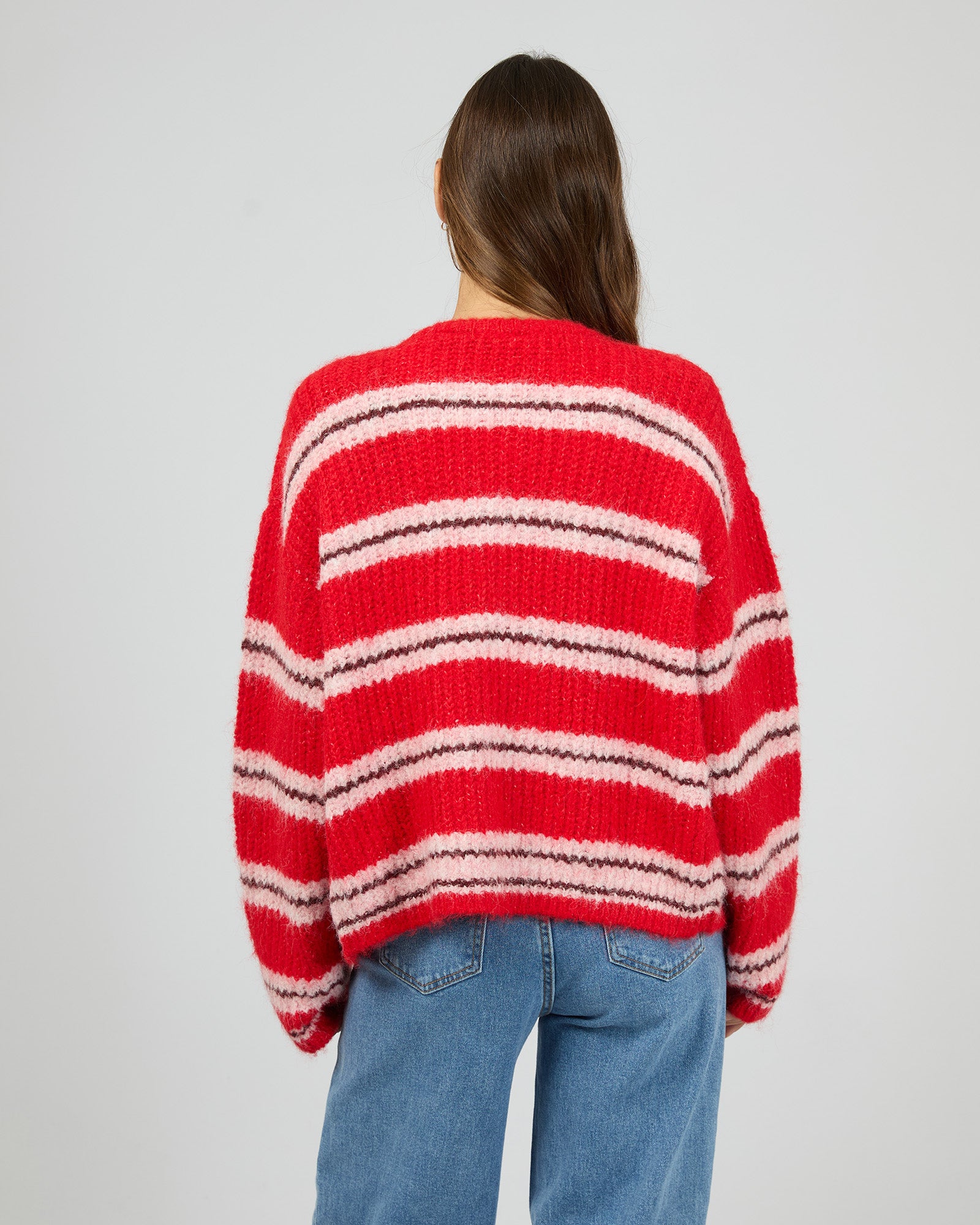 Person wearing a red and white striped sweater on a plain background