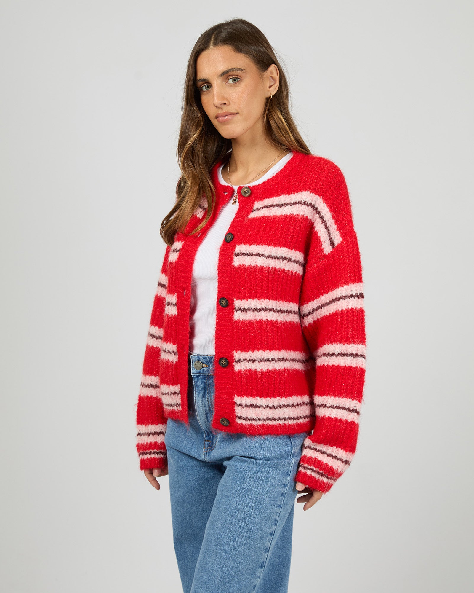 Woman wearing a red and white striped cardigan on a plain background