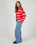 Person wearing a red and white striped sweater and blue jeans on a plain background