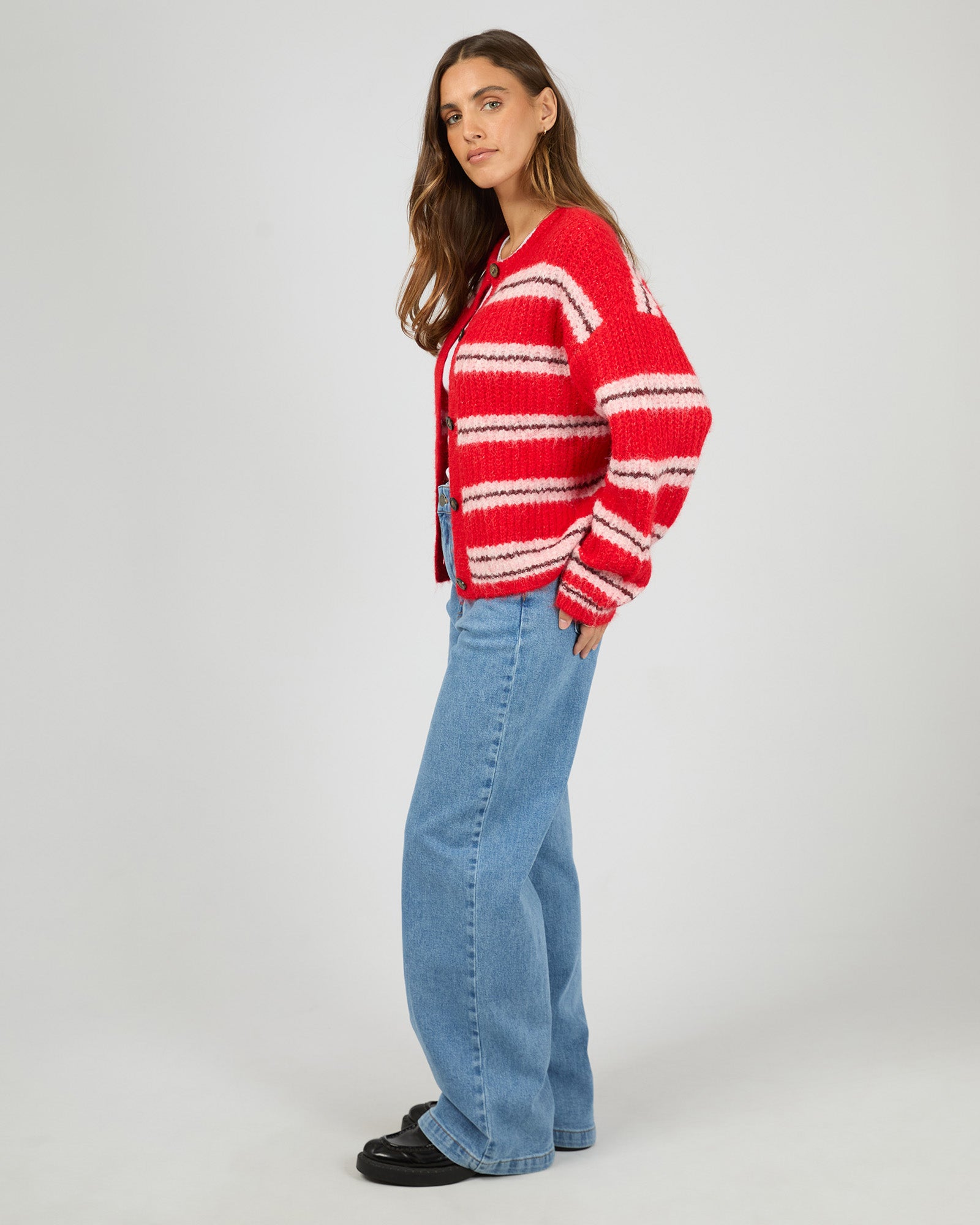 Person wearing a red and white striped sweater and blue jeans on a plain background