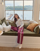 Woman sitting on a couch by a large window with a scenic view of water and mountains.