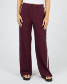 Maroon wide-leg pants with white stripes on a white background