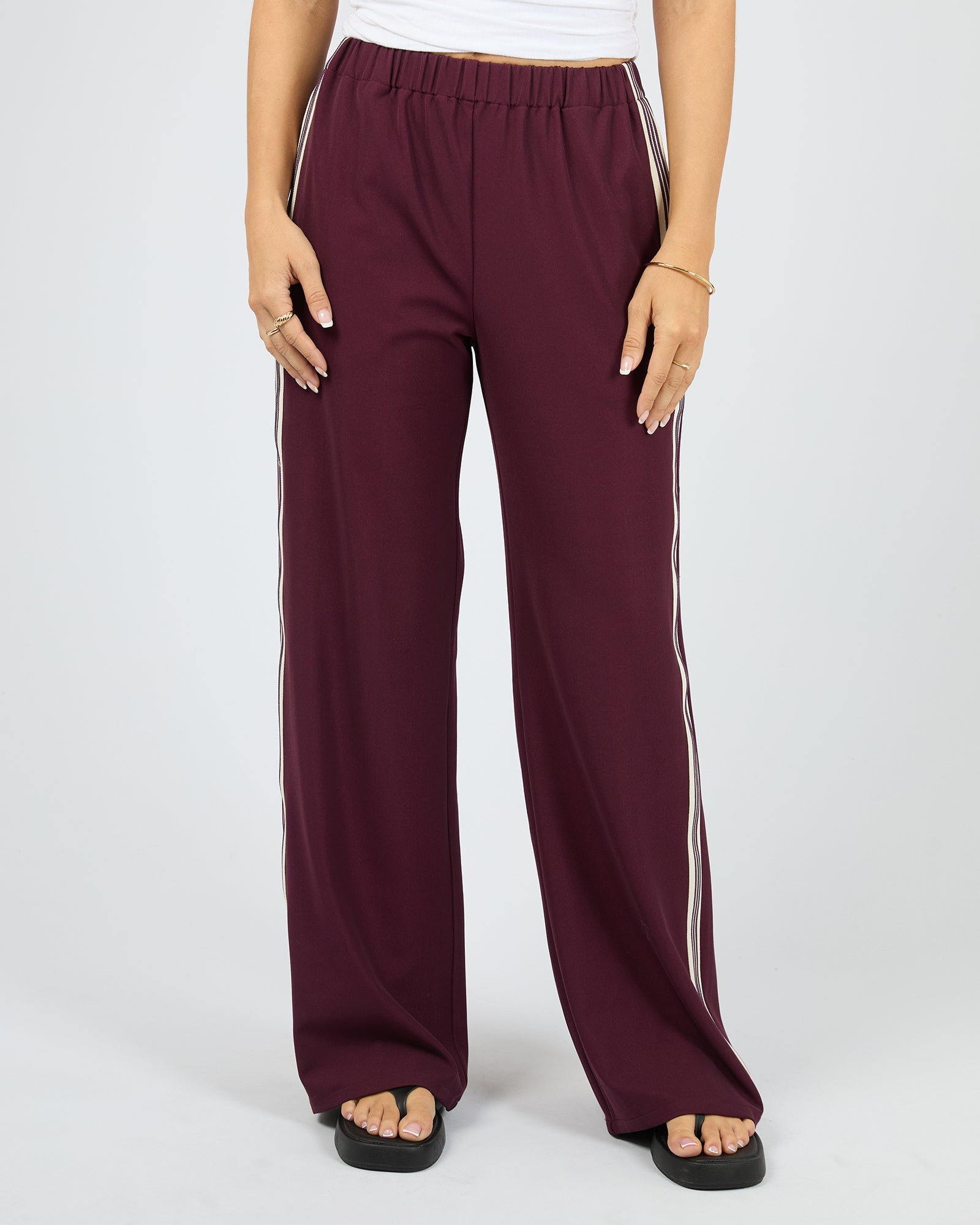 Maroon wide-leg pants with white stripes on a white background