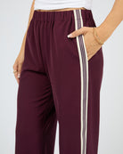 Maroon pants with white stripes on a plain background