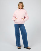 Woman wearing a pink hoodie and blue jeans on a white background