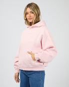 Woman wearing a pink hoodie on a light gray background