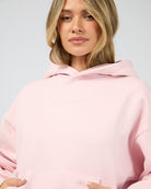 Person wearing a pink hoodie against a plain background