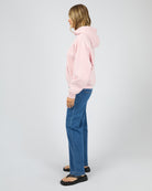 Person wearing a pink hoodie and blue jeans on a white background