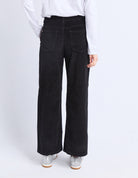 Person wearing black wide-leg jeans and a white shirt on a white background