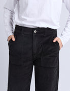 Person wearing black cargo pants with a plain background
