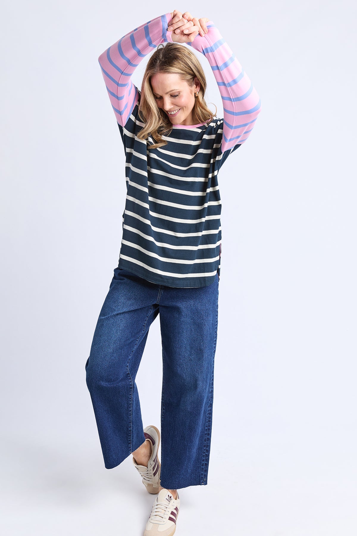Person wearing a striped shirt and blue jeans on a white background