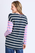 Woman wearing a striped long-sleeve shirt with pink and white stripes on a plain background
