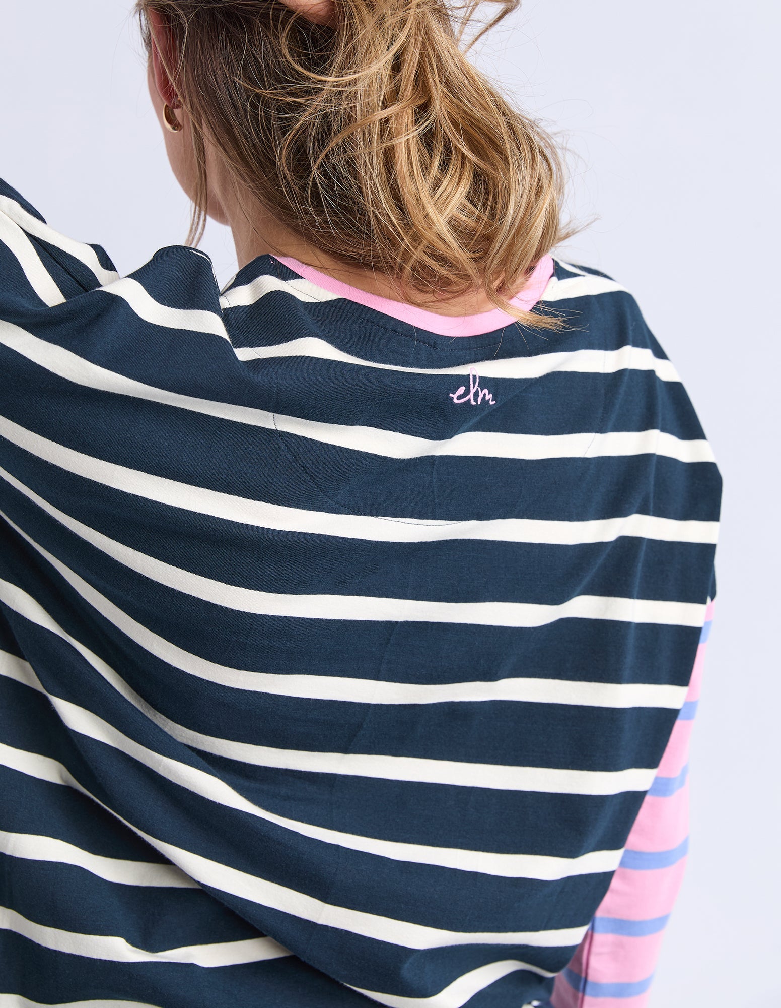 Navy and white striped shirt with colorful sleeves on a plain background