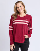 Woman wearing a red long-sleeve shirt with white stripes on a light gray background