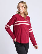 Woman wearing a red long-sleeve shirt with white stripes on a light gray background
