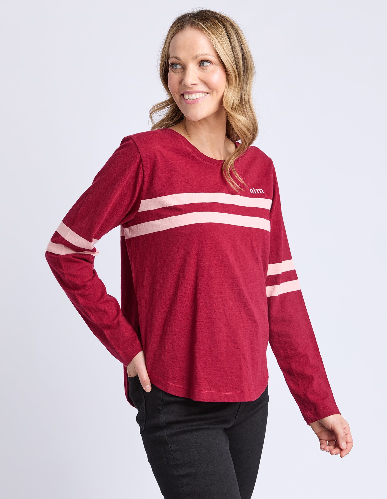 Woman wearing a red long-sleeve shirt with white stripes on a light gray background