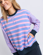Woman wearing a blue and pink striped sweater on a light gray background