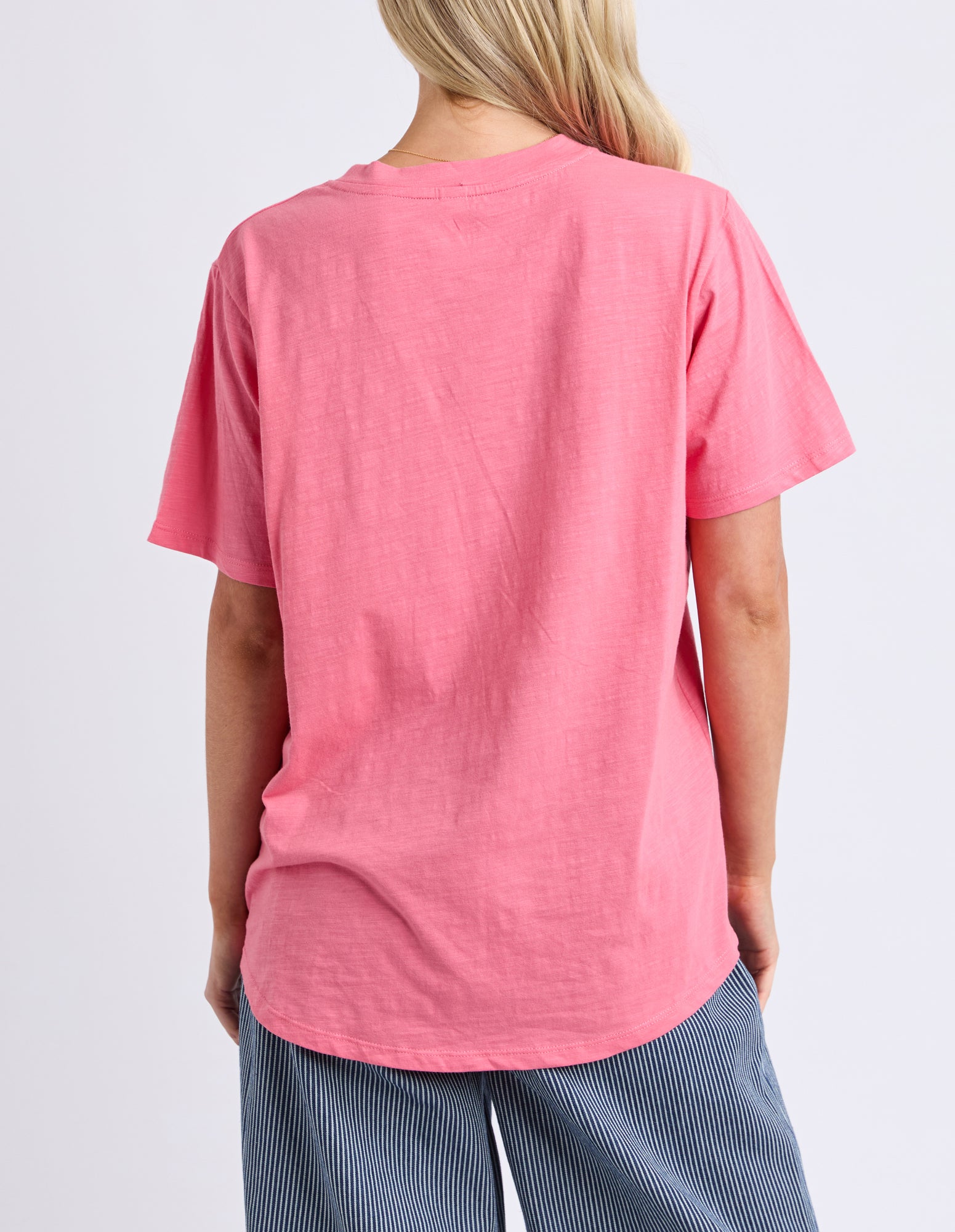 Person wearing a pink t-shirt on a light gray background