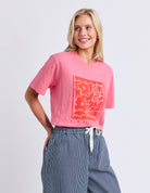 Woman wearing a pink t-shirt with a graphic design on a plain background