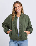 Woman wearing a green quilted jacket on a white background