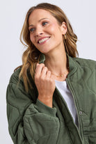 Woman wearing a green jacket with a plain background
