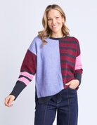 Woman wearing a colorful striped sweater with a plain background