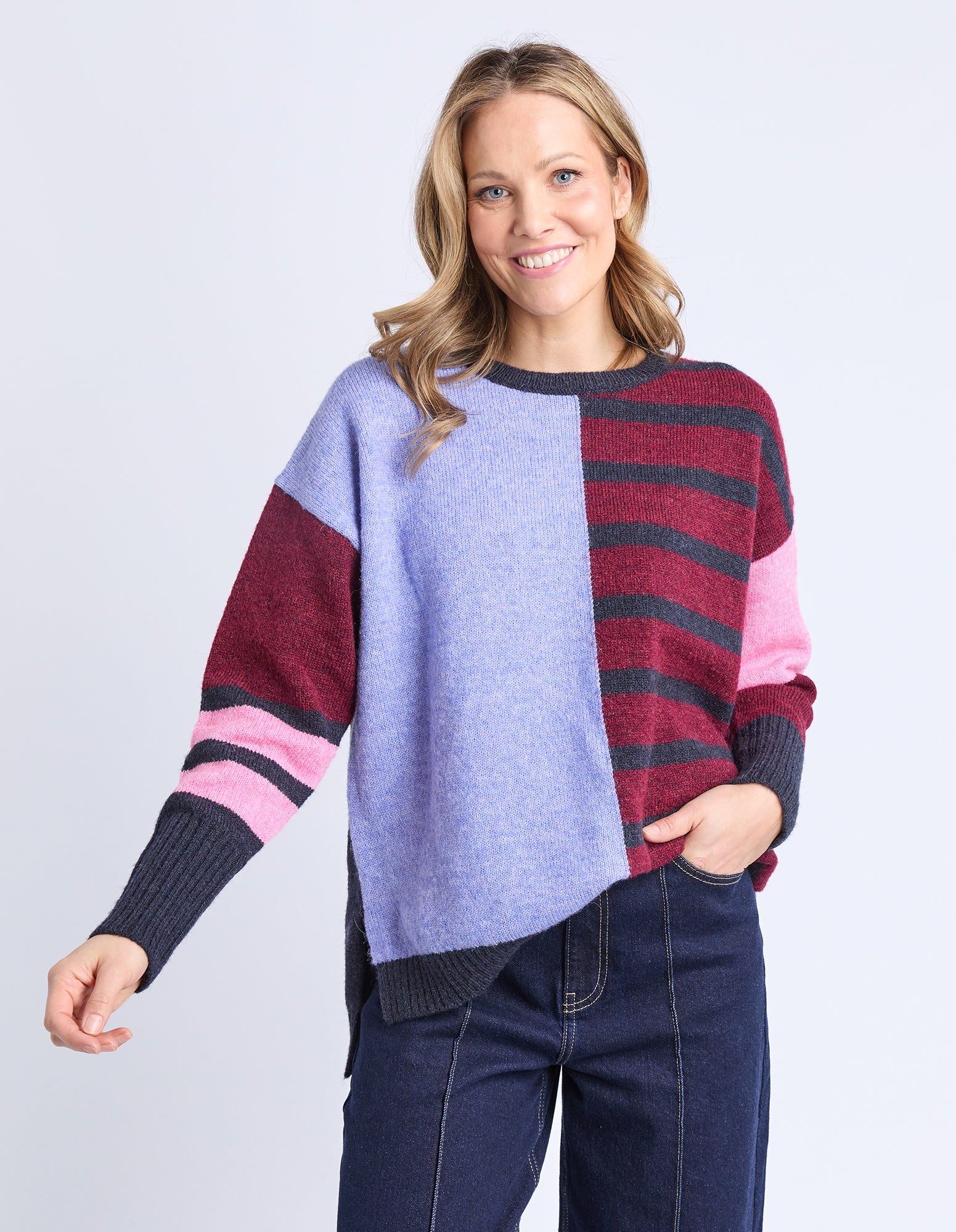 Woman wearing a colorful striped sweater with a plain background