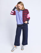 Woman wearing a colorful sweater and blue jeans on a white background