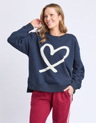 Woman wearing a navy sweatshirt with a white heart design on a light gray background