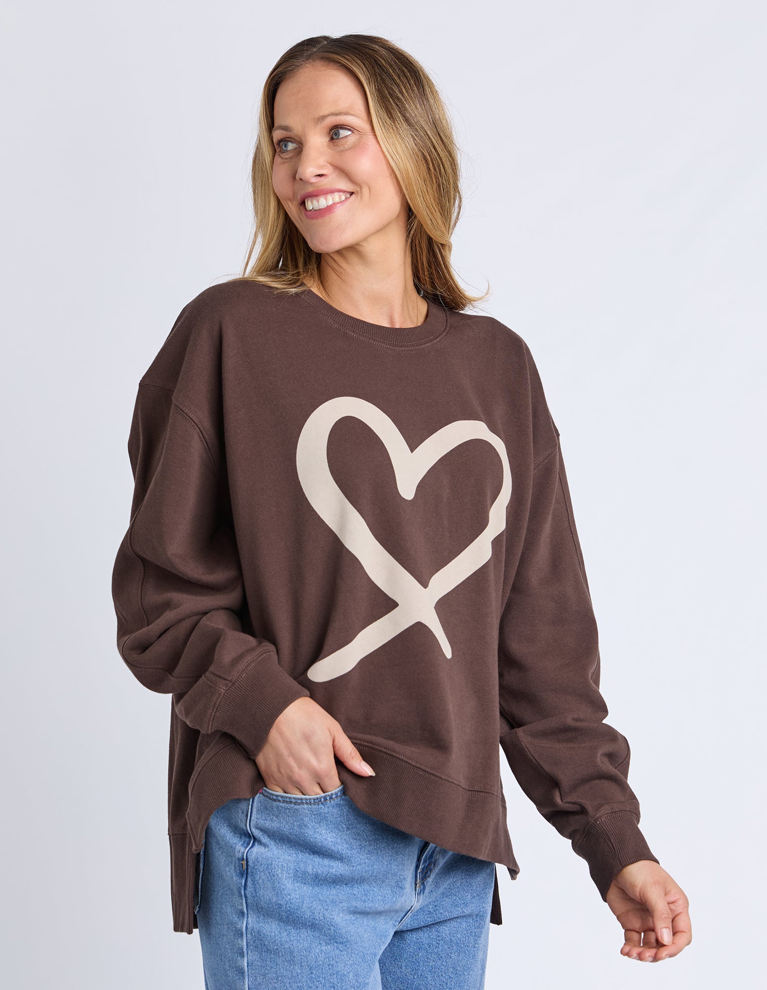 Woman wearing a brown sweatshirt with a heart design on a light gray background