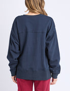 Navy blue sweatshirt worn by a person on a light purple background