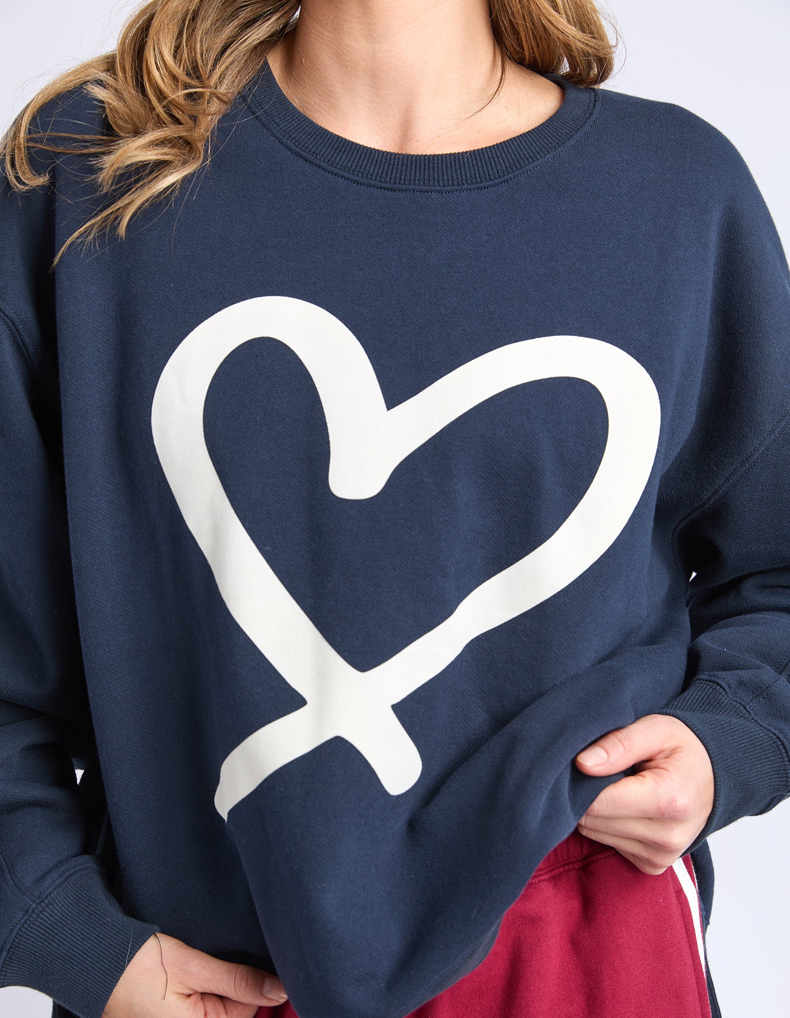 Navy blue sweatshirt with a large white heart design worn by a person.