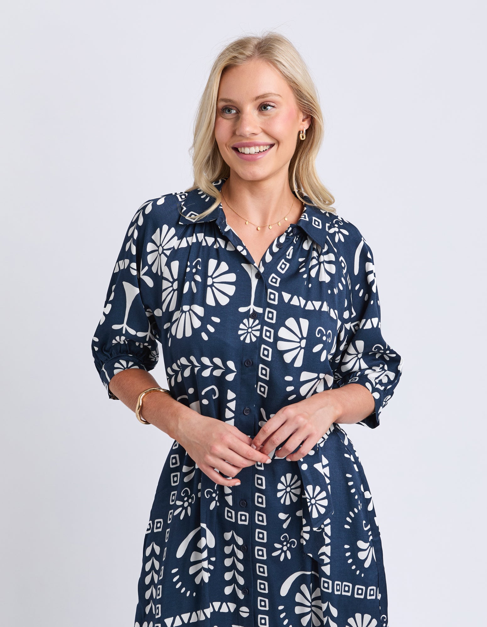 Woman wearing a navy blue dress with white geometric pattern on a light gray background