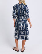 Woman wearing a navy blue dress with white patterns on a white background