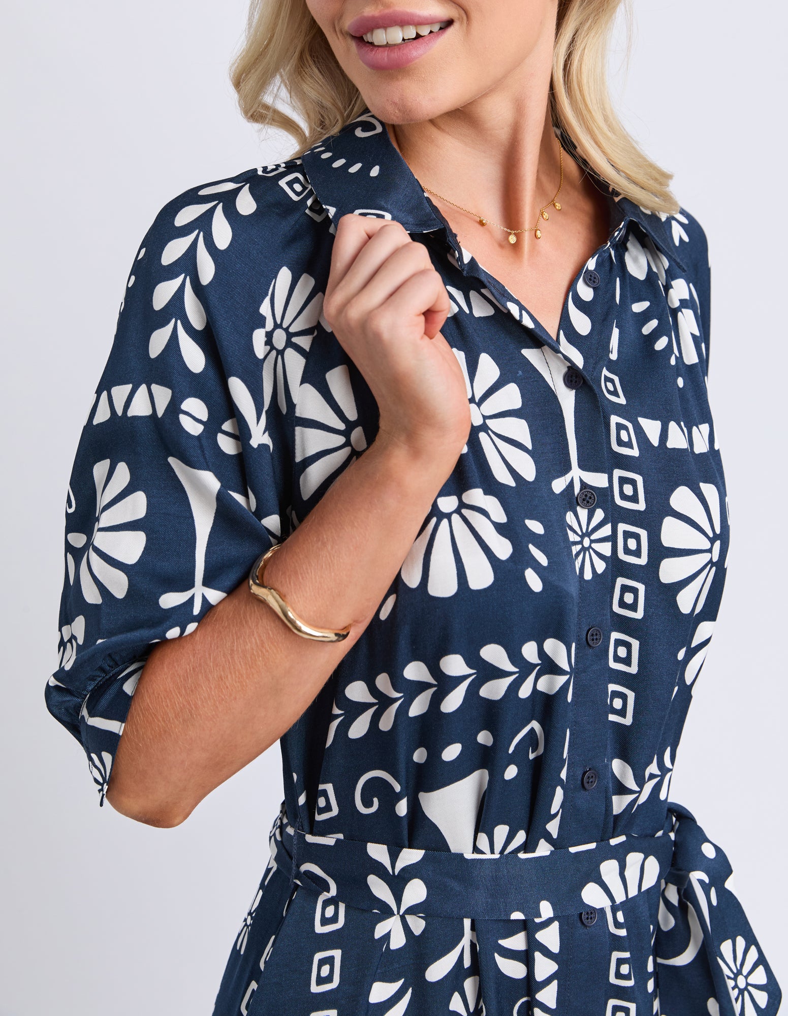 Woman wearing a navy blue dress with white geometric pattern on a plain background
